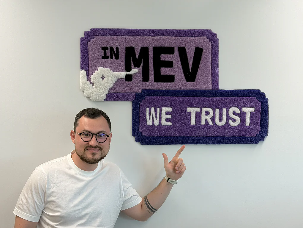 Anatolii, Kolibrio founder, in front of the 'In MEV We Trust' carpet